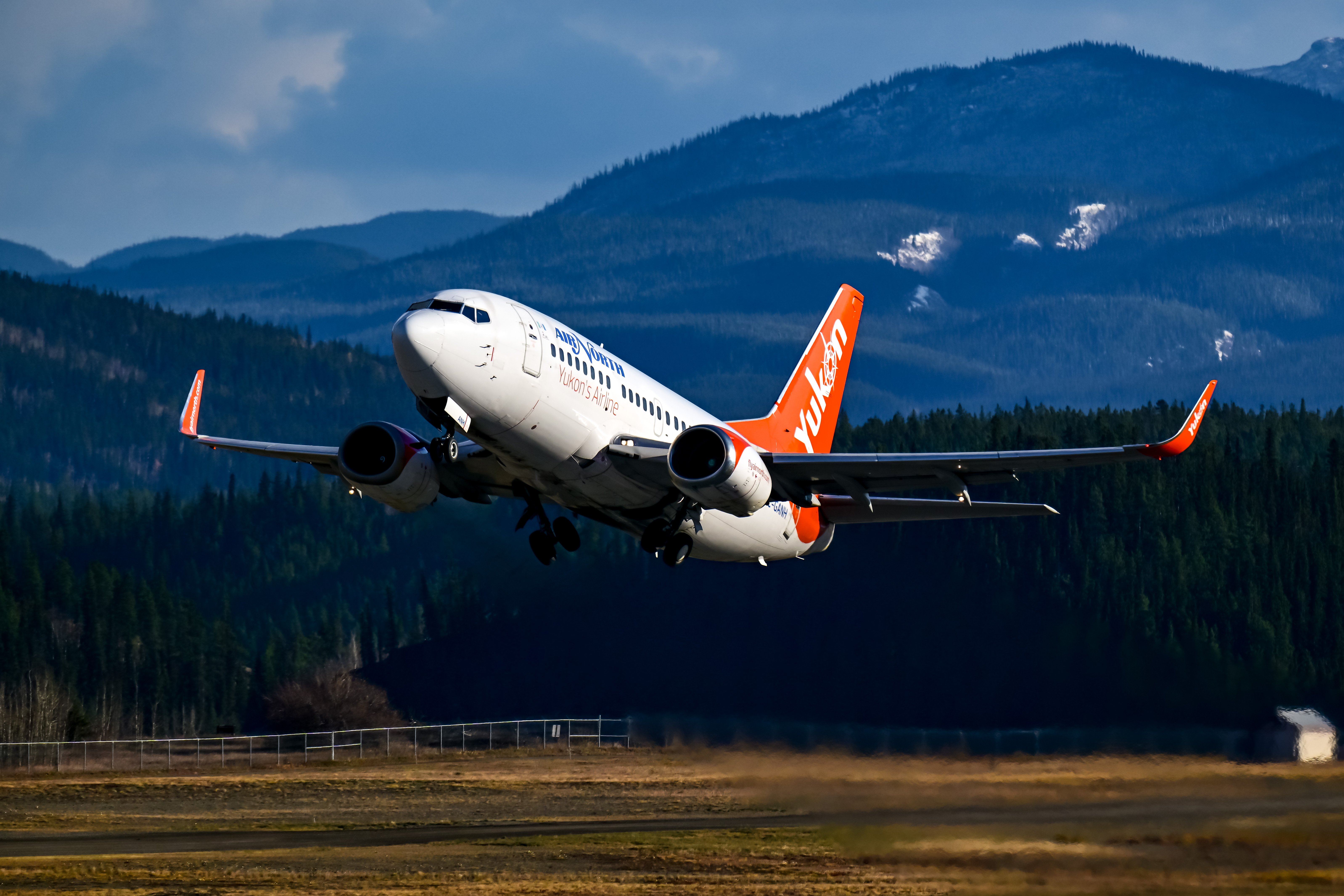 Air North Boeing 737 taking off with mountain scenery in the Yukon.