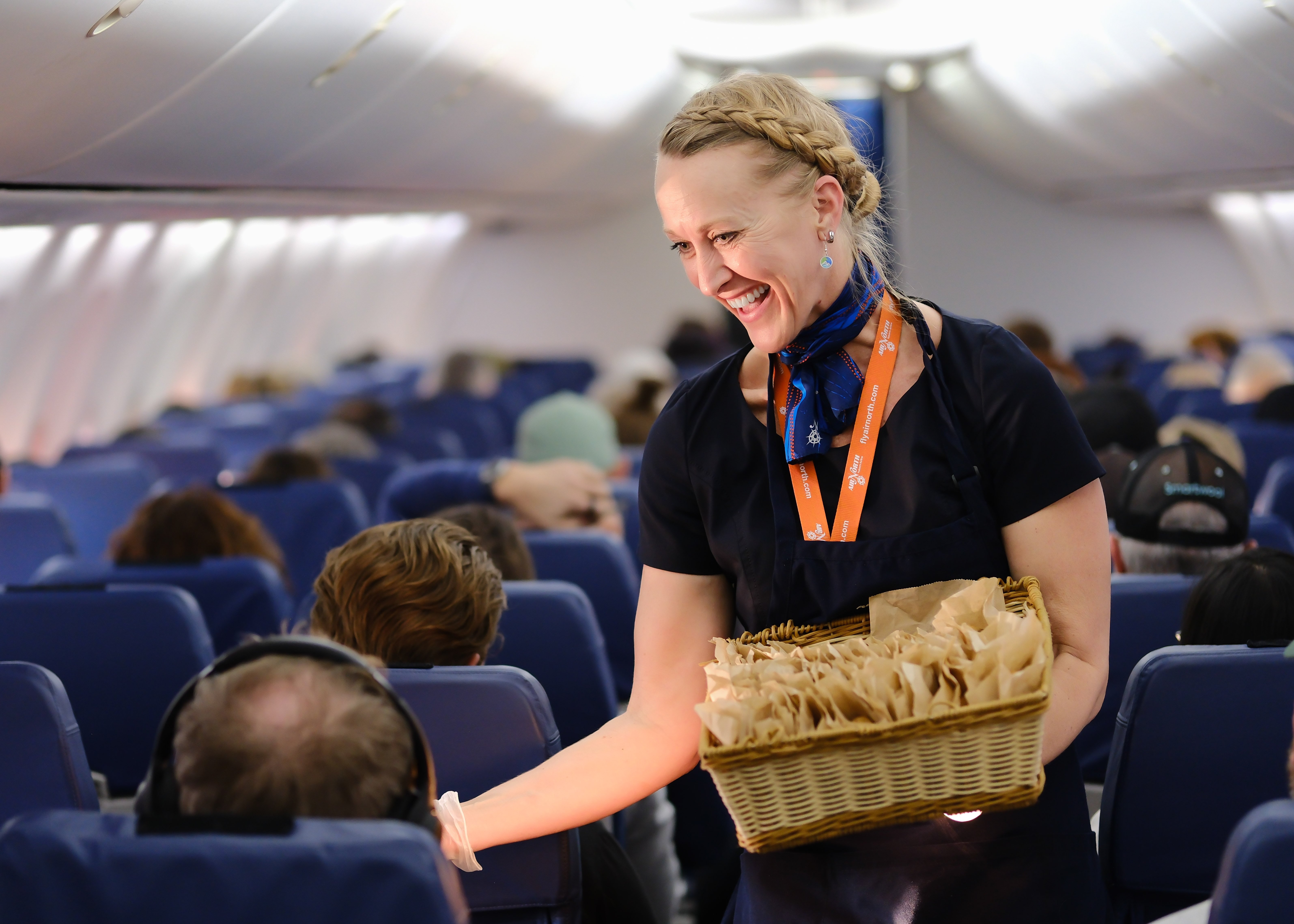 Air North flight attendant serving guests on board with warm inflight hospitality.