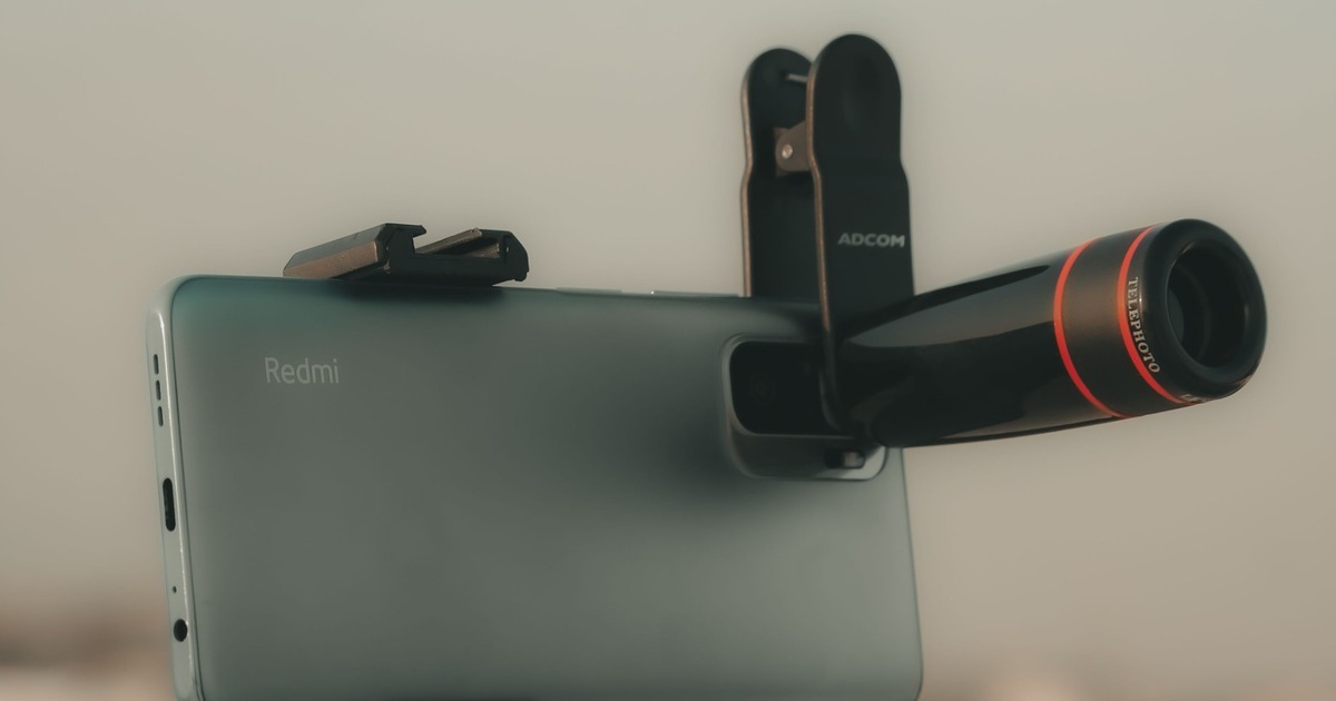 Smartphone fitted with a clip-on camera lens.
