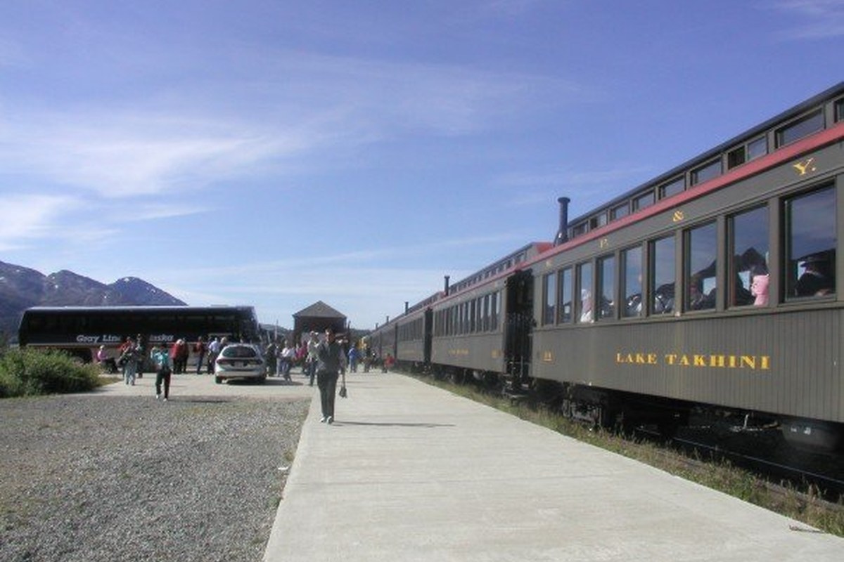 White Pass train at Fraser, British Columbia, with passengers on the platform and mountains in the background.