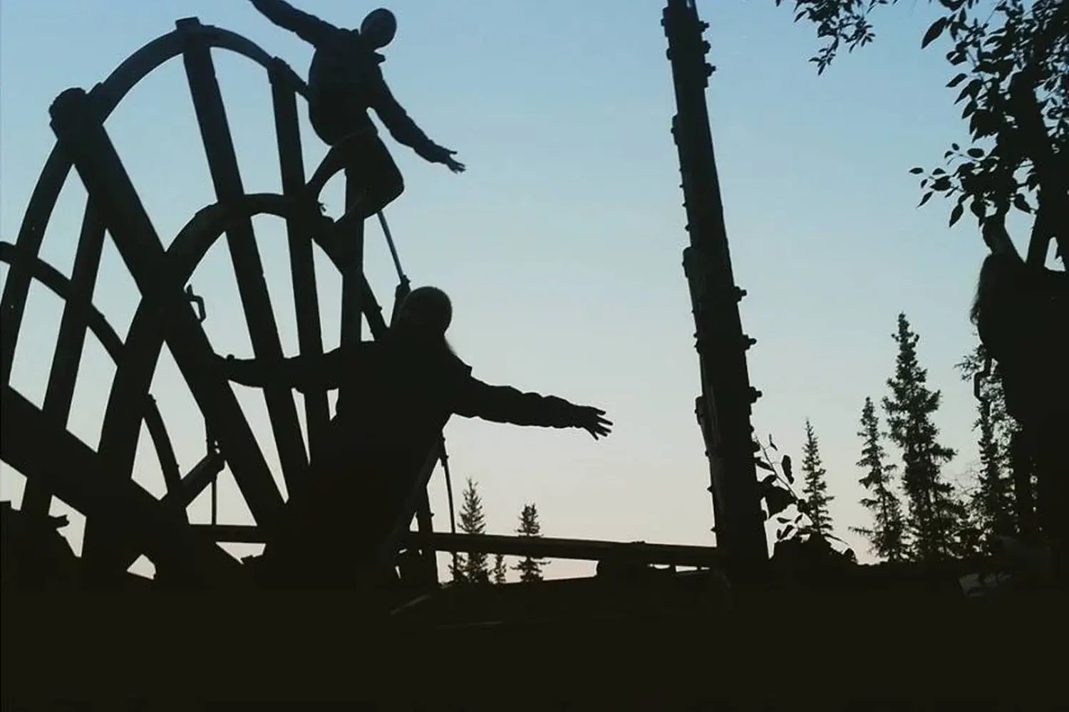 Silhouettes of guests exploring the sternwheeler graveyard in West Dawson, where the remains of old riverboats rest along the Yukon River.