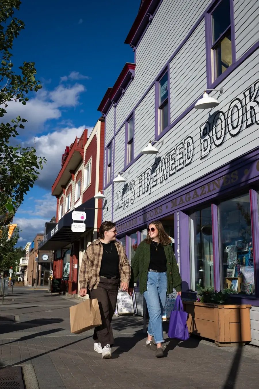 Guests shopping along Main Street in Whitehorse, with colourful historic-style storefronts under a bright Yukon sky.