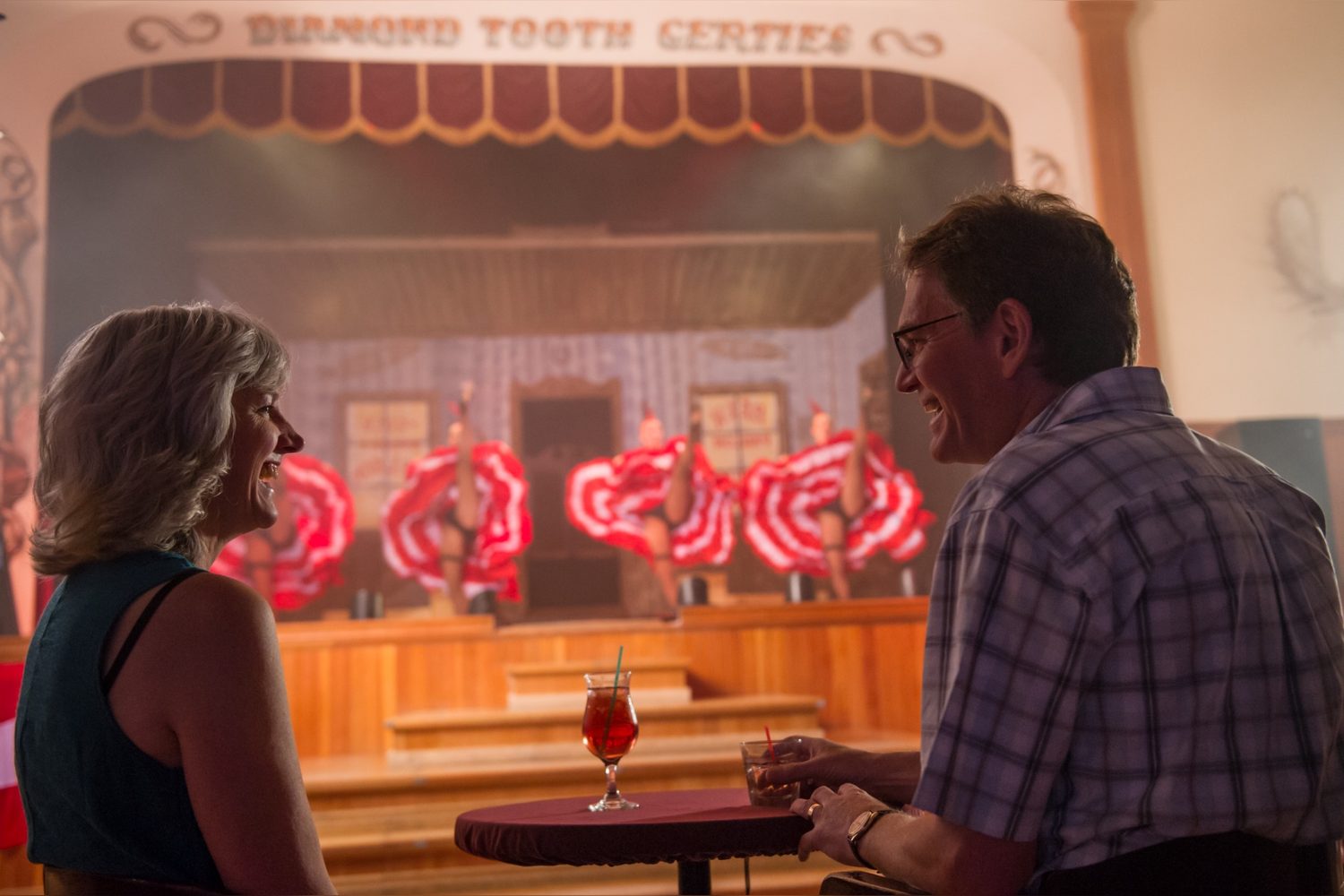 Two guests watch a cancan show at Diamond Tooth Gerties in Dawson City, with dancers performing on stage in the background. Two guests watch a cancan show at Diamond Tooth Gerties in Dawson City, with dancers performing on stage in the background.